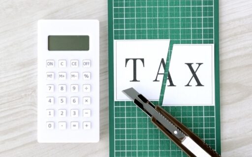 Calculator, scissors, and paper with 'TAX' written on it, symbolizing tax planning and strategies for retirement.