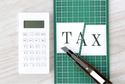 Calculator, scissors, and paper with 'TAX' written on it, symbolizing tax planning and strategies for retirement.